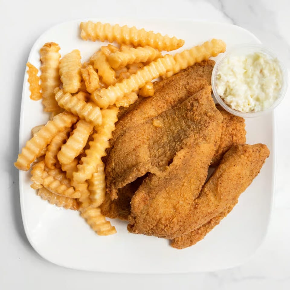 Fried fish fillets with crinkle-cut fries and a side of coleslaw on a white plate.